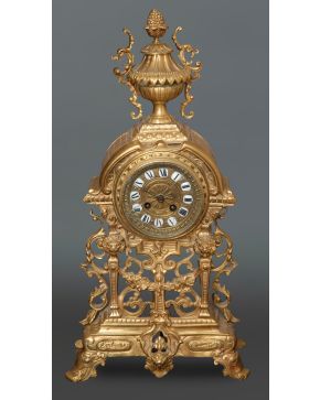 2253-Reloj de sobremesa francés en bronce dorado, s. XX, con remate de copa. Esfera dañada. Con péndulo y llaves. Altura: 56 cm. 