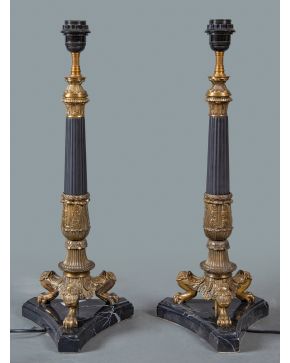 2254-Pareja de lámparas de sobremesa estilo Imperio en bronce dorado y mármol negro Marquina. Fuste estriado sobre patas de garra de león.  